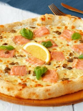 Pizza z łososiem, cytryną i bazylią na drewnianej desce