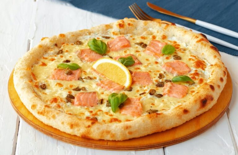 Pizza z łososiem, cytryną i bazylią na drewnianej desce